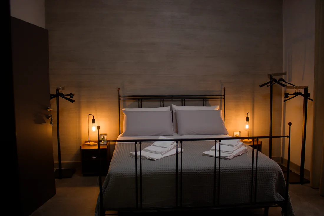 La camera con il letto in ferro battuto e le lampade accese sui comodini