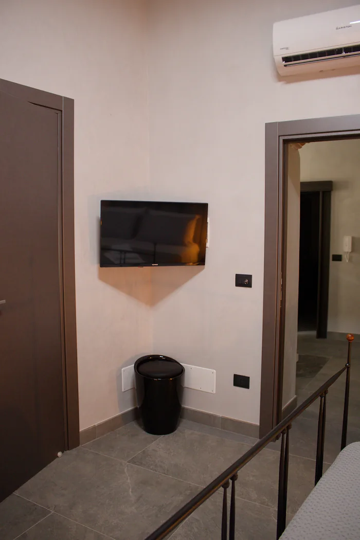 L'angolo della camera con il televisore, il condizionatore e la porta che d&agrave; sul pianerottolo