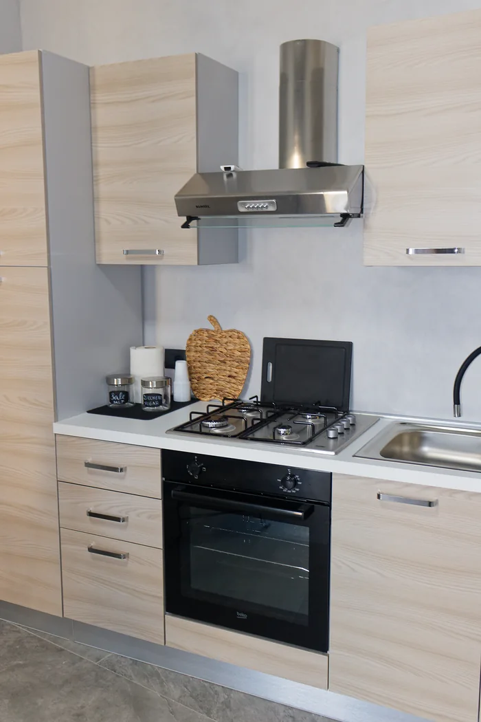 La cucina: il piano cottura sotto la cappa, il forno e i barattoli del sale e dello zucchero