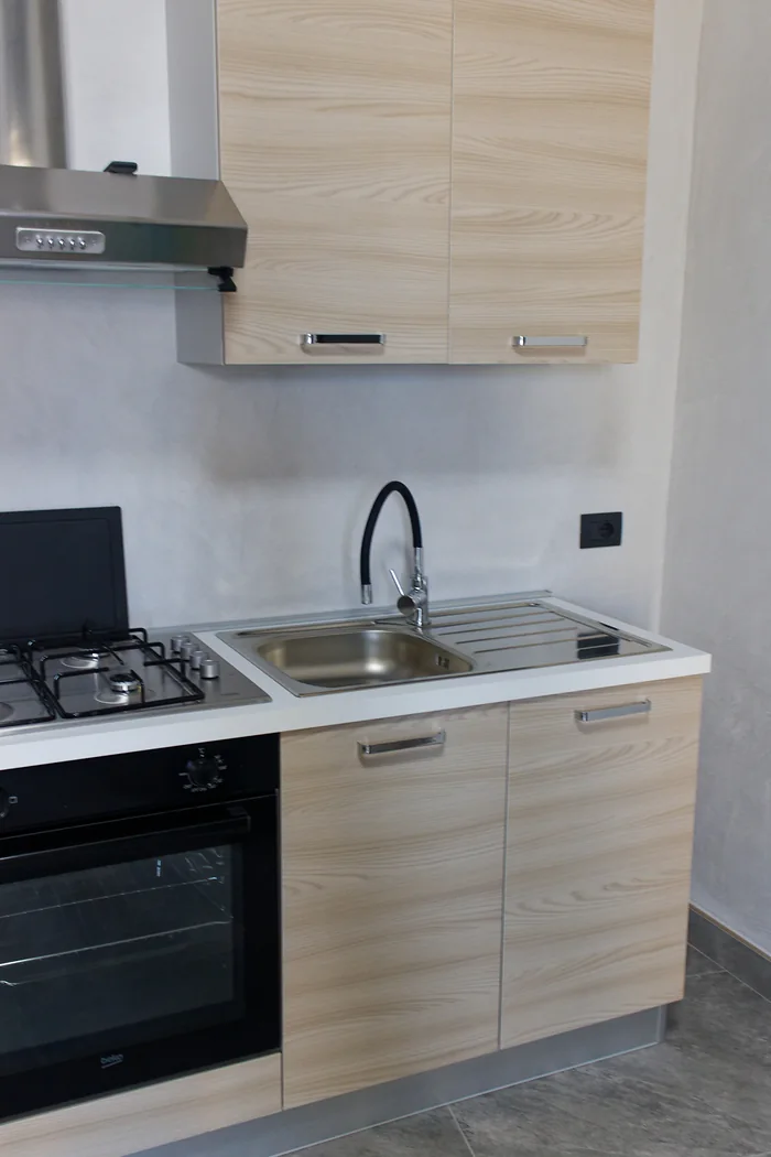 Il lavello della cucina con il rubinetto nero e lo scolapiatti, accanto al piano cottura